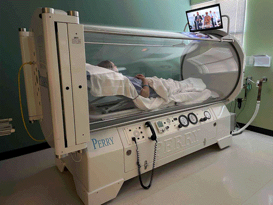 A man lying in bed with a TV above him for Hyperbaric Oxygen Therapy in the Dallas Metro Area.