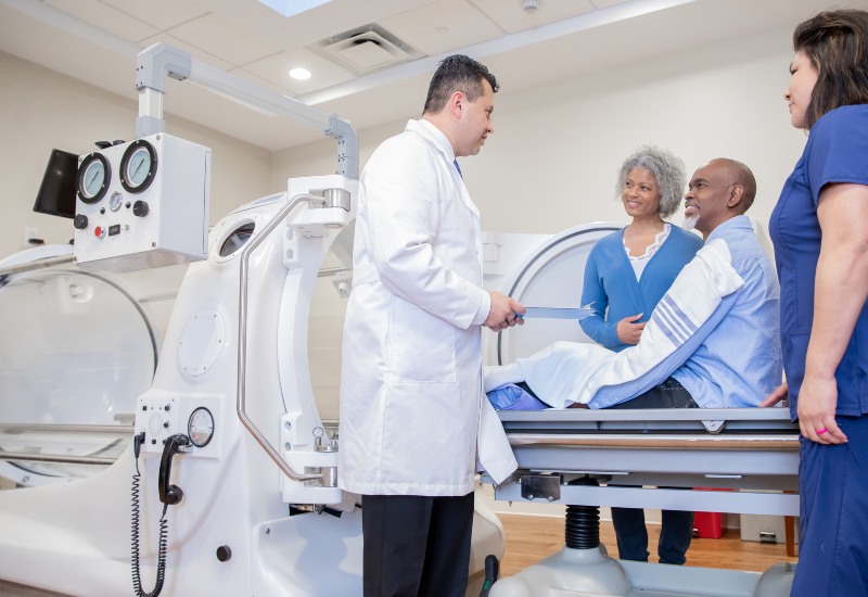 A doctor and nurses converse with a patient for gas gangrene treatment in the Dallas Metro Area.