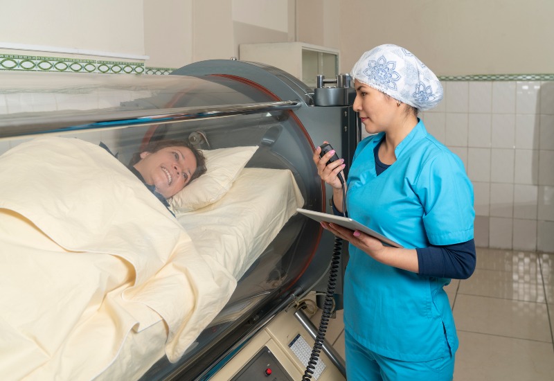 A nurse converses with a patient in the Dallas Metro Area, providing HBOT for overall wellness.
